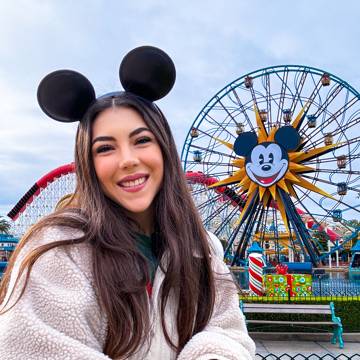 Dani Godinez con orejas de Mickey frente a la rueda de la fortuna Pixar Pal-A-Round en Disney California Adventure